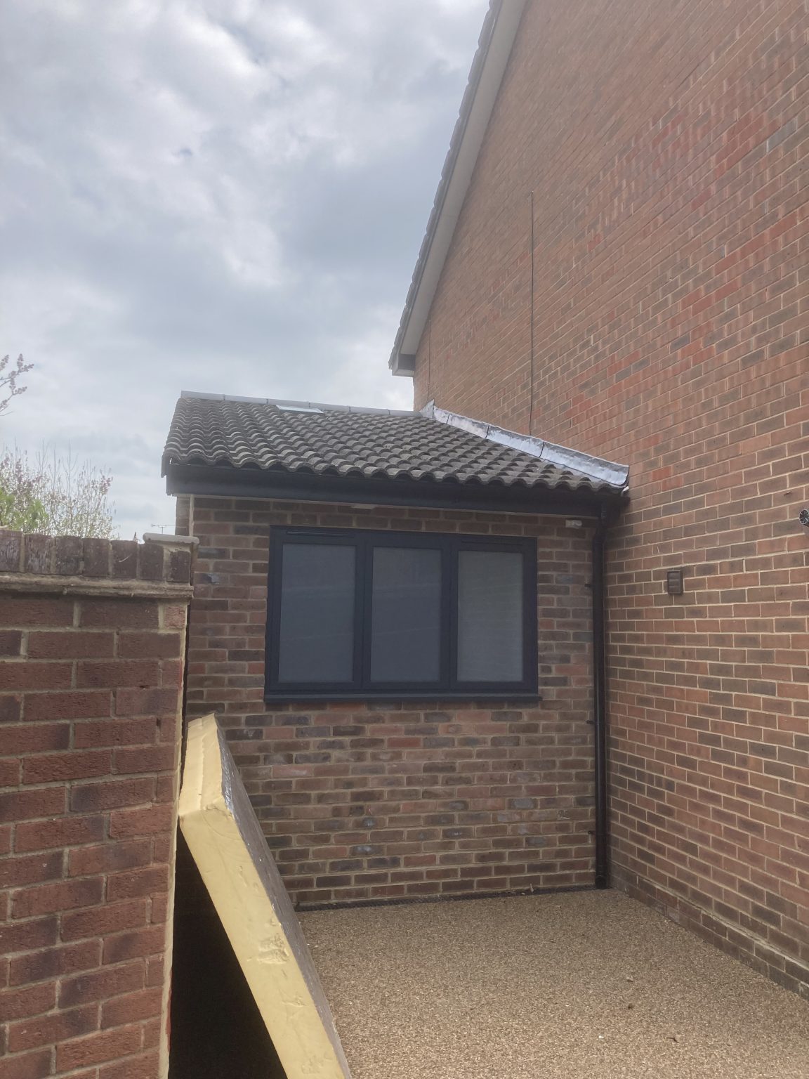 Brick-built extension with a tiled roof and dark window frames
