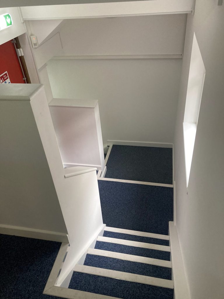 Staircase finished in white with a navy carpet runner