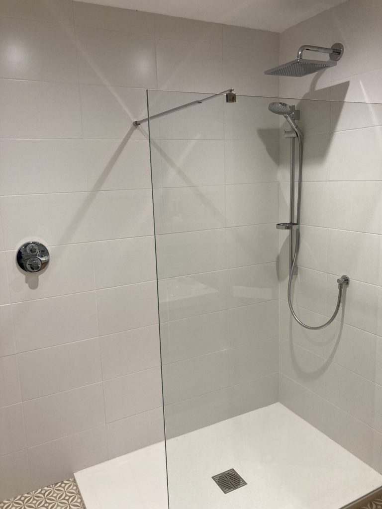 Walk-in shower with a glass screen, rainfall head and white tiling